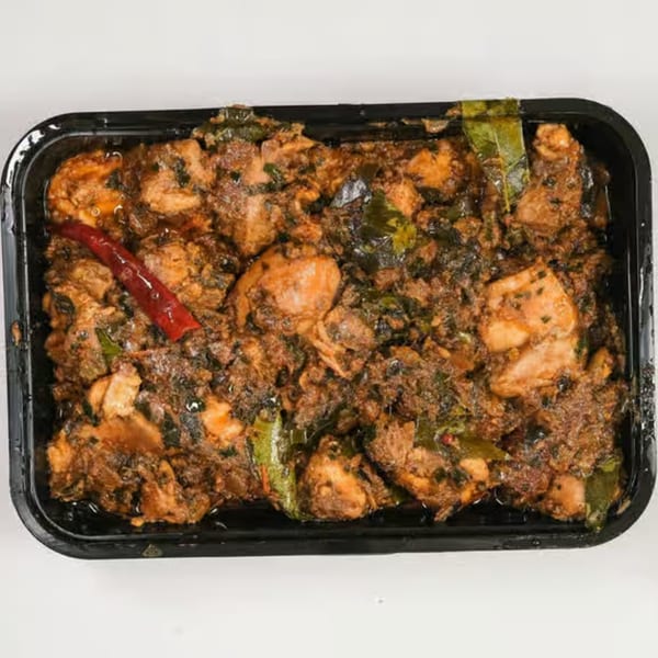 UlavacharU Indian Restaurant's chicken curry, rich with spices and green herbs, in a black container.