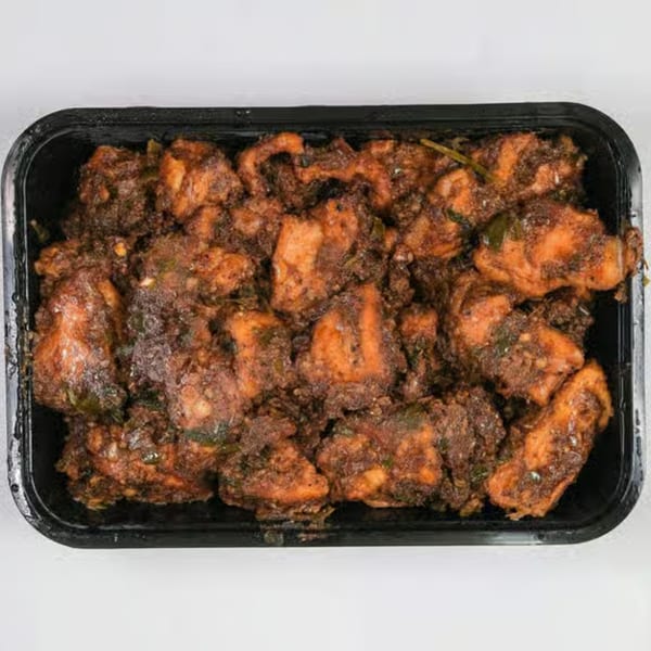 Close-up of UlavacharU Indian Restaurant's flavorful chicken curry in a black takeout container.